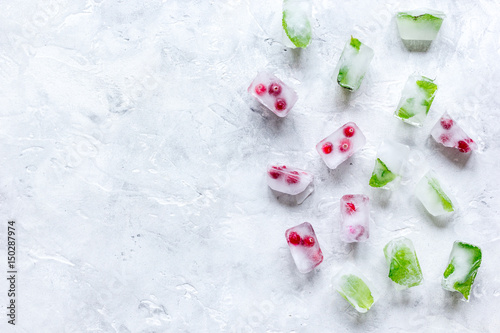 Ice cubes with berries and mint stone background top view mock up