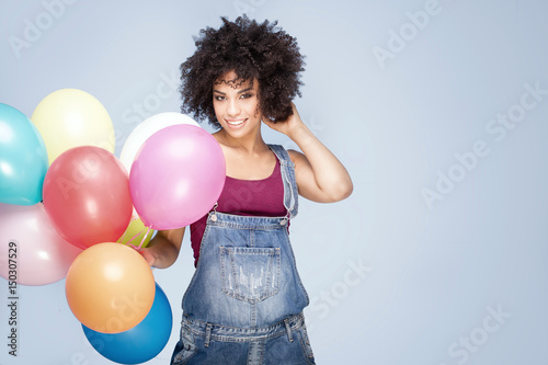 Happy young girl with afro holding balloons.