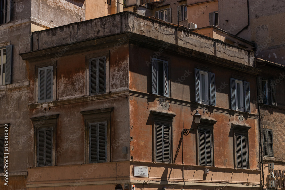 fragment starego włoskiego domu z zamkniętymi okiennicami w pełnym słońcu