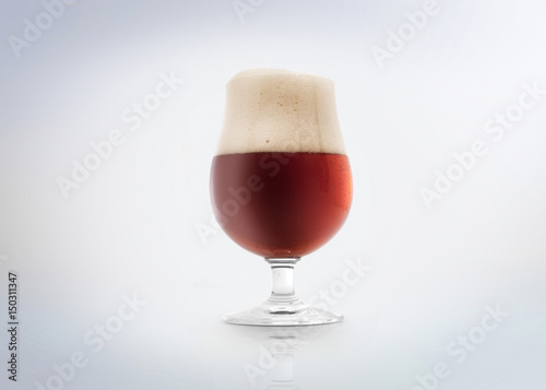Glass of a belgian amber ale beer with foam. Isolated on white background.