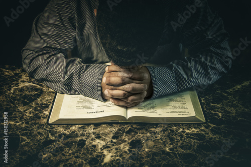 Photos Man praying to God on an open Bible