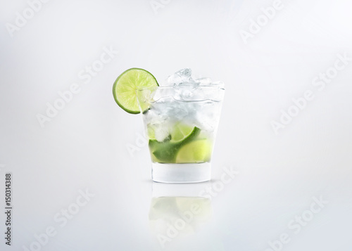 A glass of a alcoholic cocktail drink of caipirinha or mojito with fresh lemon on the glass and ice. Isolated on white background. photo