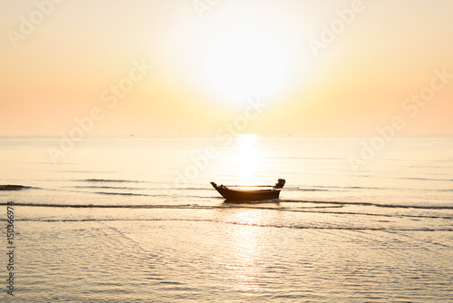 Silhouette of fishing boat and Beautiful tropical sunrise on the beach.