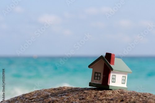 A toy house on a background of sea waves. Sandy beach.