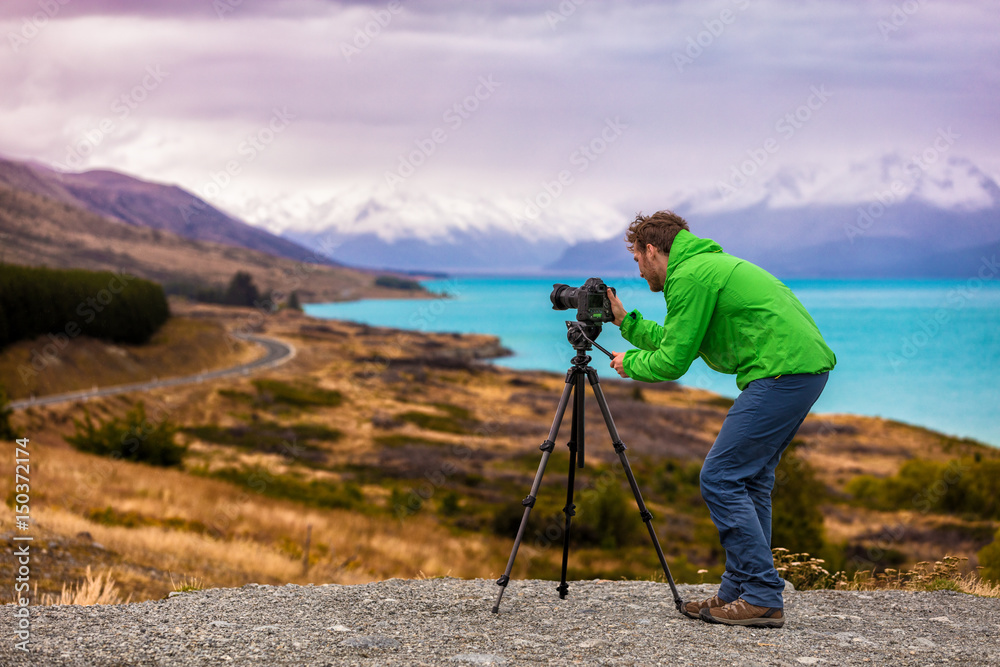 Travel photographer taking nature landscape pictures in New Zealand at sunset. Man shooting at Peter's lookout, famous tourist attraction at Pukaki Lake.
