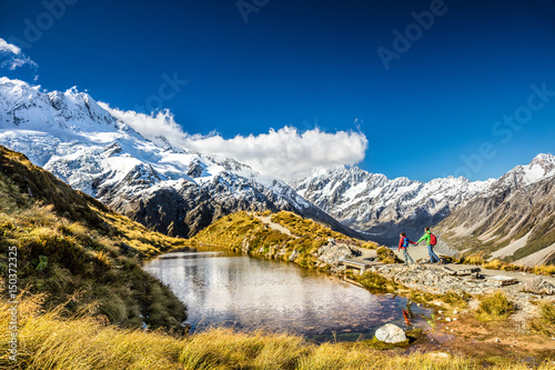 Hiking travel nature hikers in New Zealand. Couple people walking on Sealy Tarns hike trail route with Mount Cook landscape, famous tourist attraction. photo