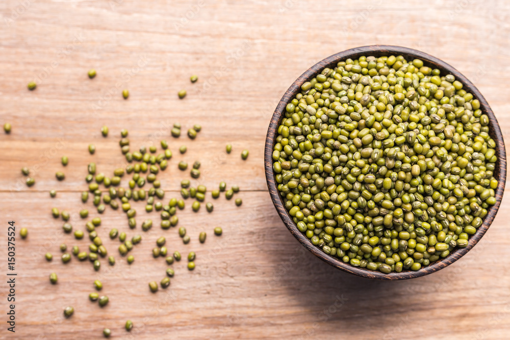 Mung beans in wooden bowl put on wooden plank background Mung beans in wooden bowl put on wooden plank background