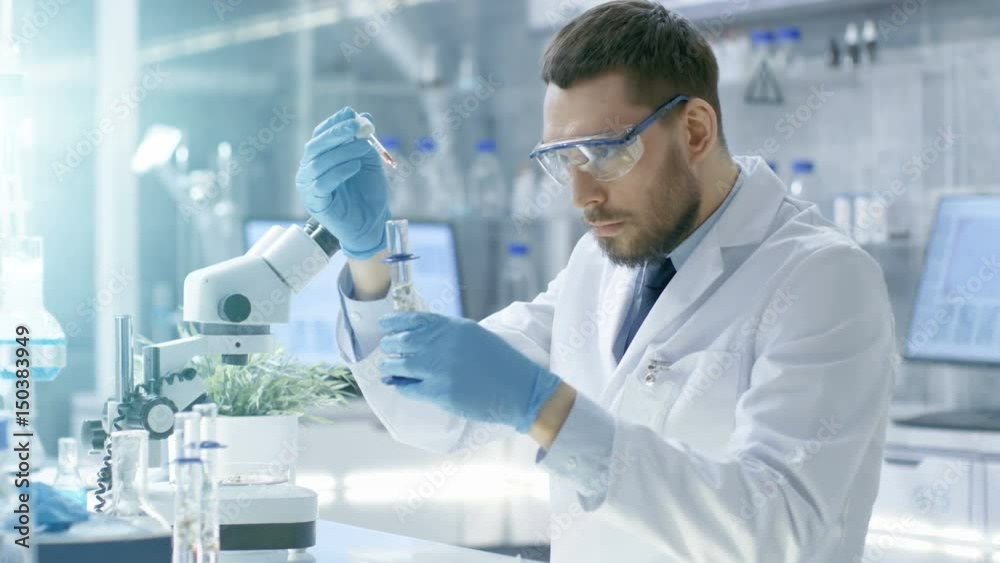 In a Modern Laboratory Scientist Conducts Experiments by Synthesising Compounds with use of Dropper and Plant in a Test Tube. Shot on RED EPIC-W 8K Helium Cinema Camera.