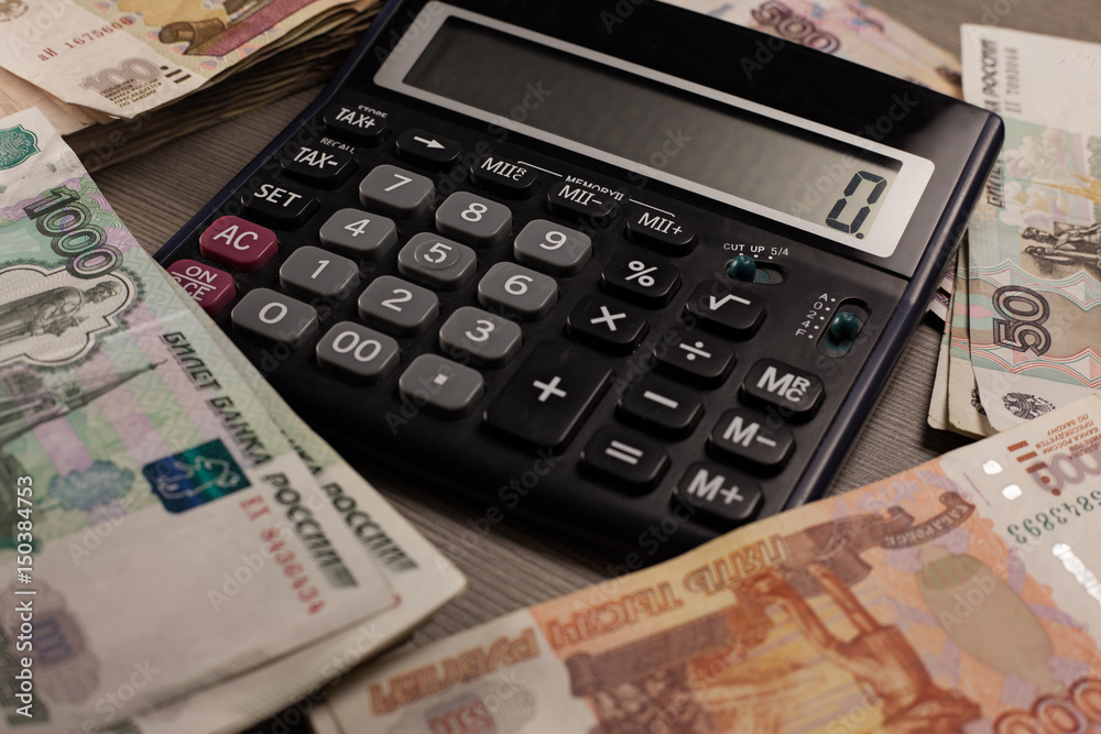 A lot of russian money and calculator on a wooden background. A lot of russian money and calculator on a wooden background.