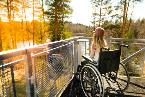 Young girl in a wheelchair on a balcony looking at the nature in the spring