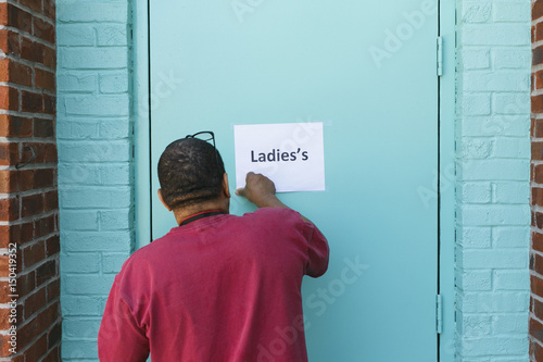man putting up a sign stating the ladies room