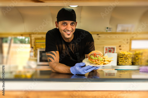 Fotografering Smiling vendor with burger