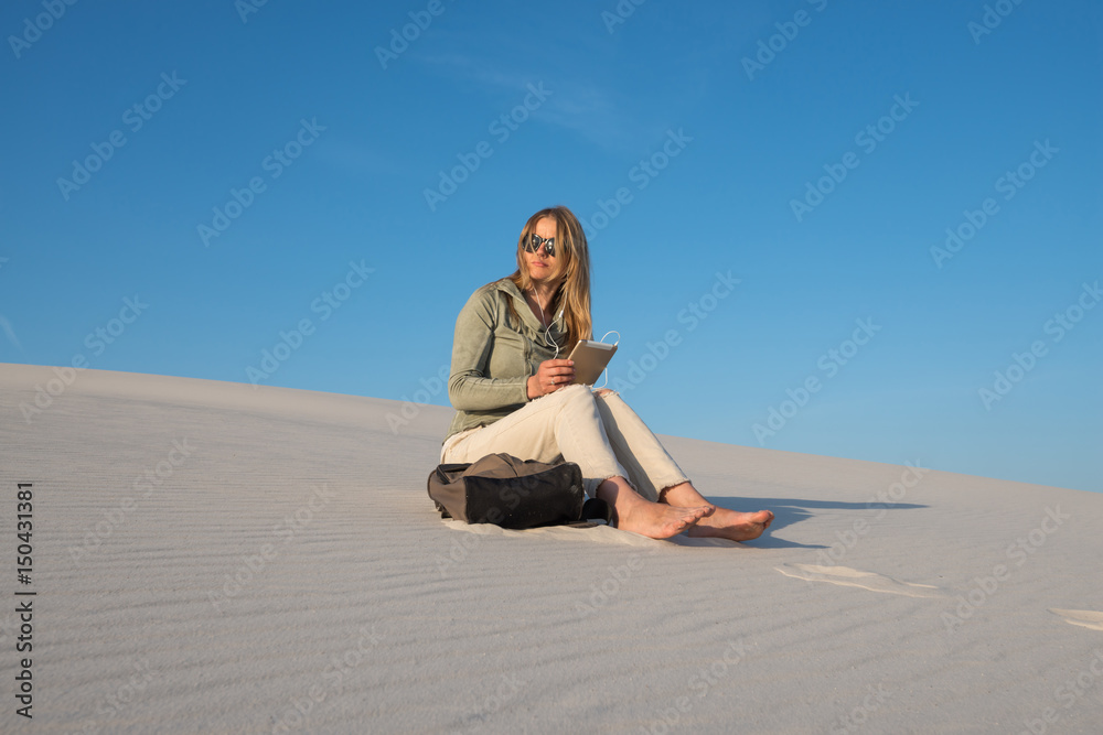 Romantic young woman, blonde sits with digital tablet in the beach