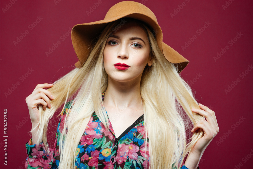 Pretty Woman with Professional Makeup in Hat and Colorful Shirt is Posing on Pink Background in Studio. Pretty Woman with Professional Makeup in Hat and Colorful Shirt is Posing on Pink Background in Studio.