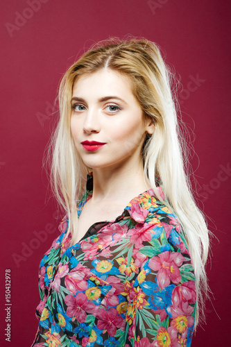 Cute Smiling Blonde with Sensual Lips Wearing Colorful Shirt on Pink Background. Portrait of Amazing Woman with Long Hair in Studio. © Andriy