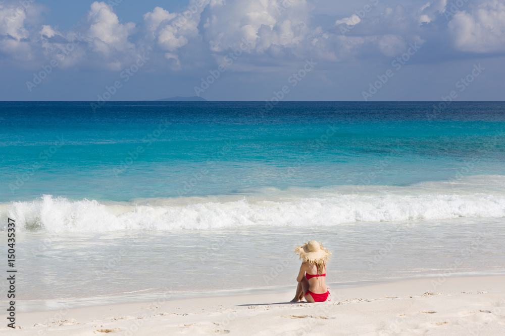 Colorful ocean beach, slim woman in red swimsuit and straw sun hat Colorful ocean beach, slim woman in red swimsuit and straw sun hat