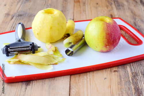 Foto Pealed apples wih the core taken away with special knives on a white cutting board on a wooden background