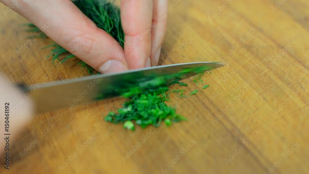 Woman with knife cutting dill in the kitchen. Woman with knife cutting dill in the kitchen.
