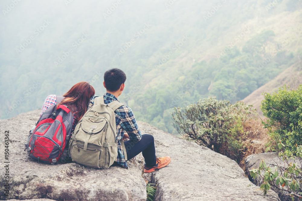 Hikers couple with backpacks on top of a mountain and enjoying nature view