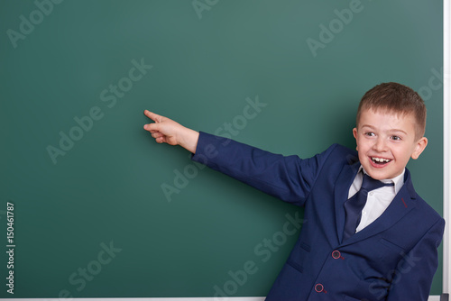 school boy point the finger near blank chalkboard background, dressed in classic black suit, group pupil, education concept
