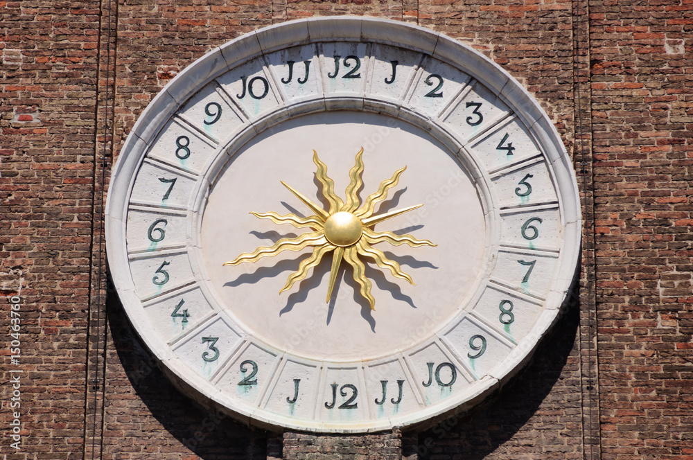 Ancient clock of Saints Apostles church in Venice with golden sun hands in the center