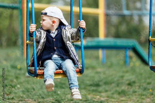Little boy riding a swing in park playground