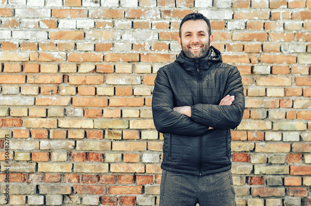 Close up portrait of happy man with beard smiling standing near a brick wall Close up portrait of happy man with beard smiling standing near a brick wall
