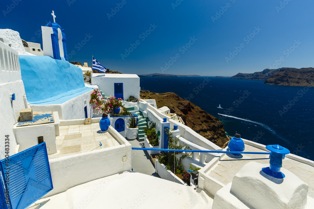 Fototapeta Picturesque view of Old Town Oia on the island Santorini, white houses, windmills and church with blue domes, Greece