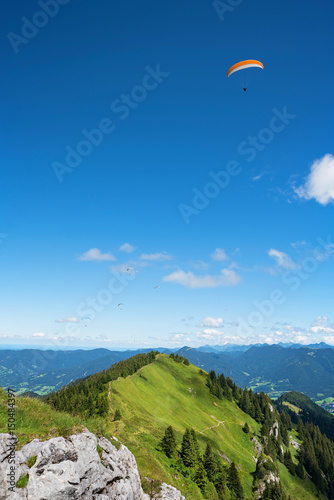 Brauneck Gipfel mit Gleitschirmflieger und blauem Himmel