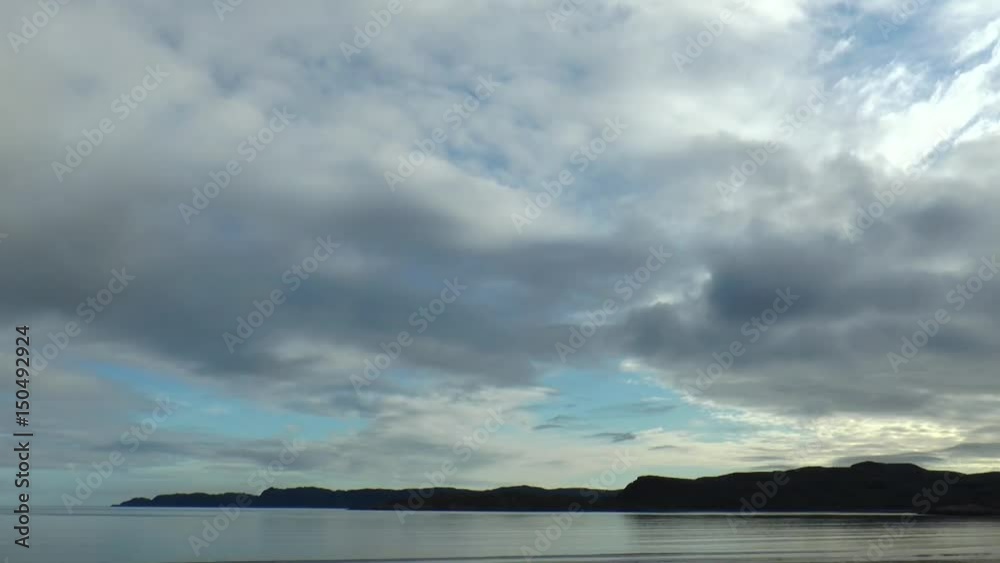  Sea and cape in the distance against the background of rapidly moving clouds, timelapse.
