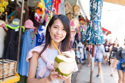 Young woman shopping at street and enjoy coconut juicy