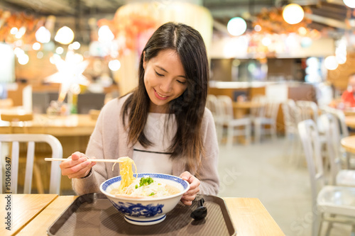 Woman eating ramen in restaurant