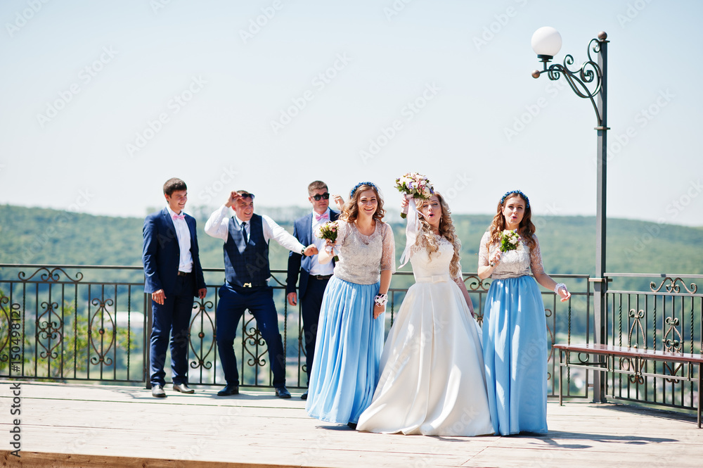 Wedding couple with bridesmaids on blue dresses and best mans having fun at wedding day.