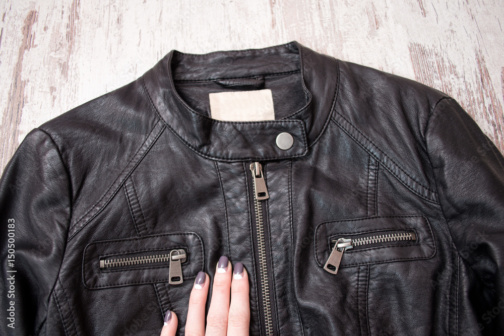 Black leather jacket with a zipper and a female hand. Fashion concept, close up Black leather jacket with a zipper and a female hand. Fashion concept, close up