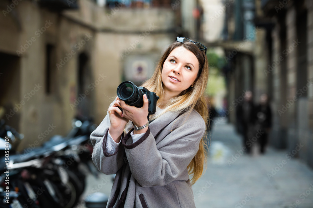 Girl holding camera in hands and photographing in the city