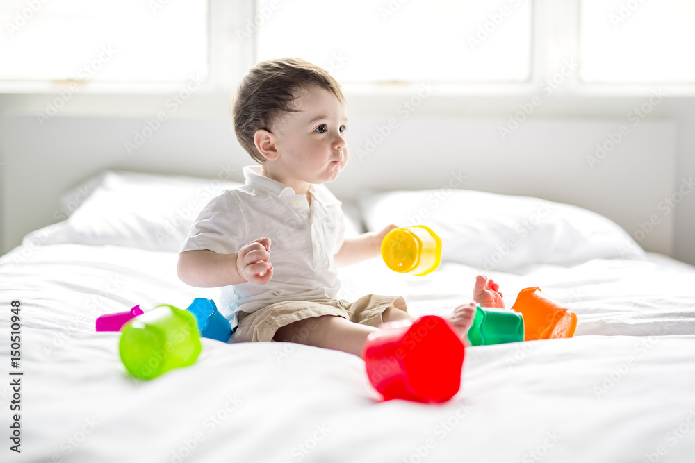 baby lying in the bed on white blanket. Cute boy playing with cubes baby lying in the bed on white blanket. Cute boy playing with cubes