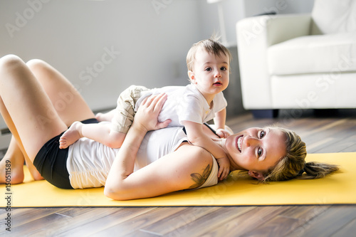 sports mother is engaged in fitness and yoga with a baby at home