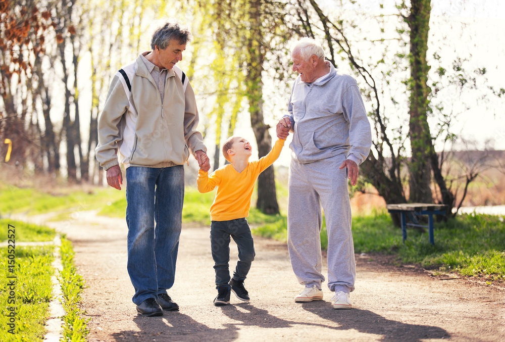 Two grandfather walking with the grandson in the park