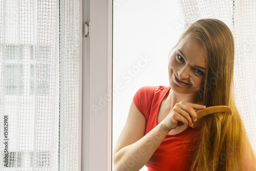 Woman sitting on windowsill brushing her hair