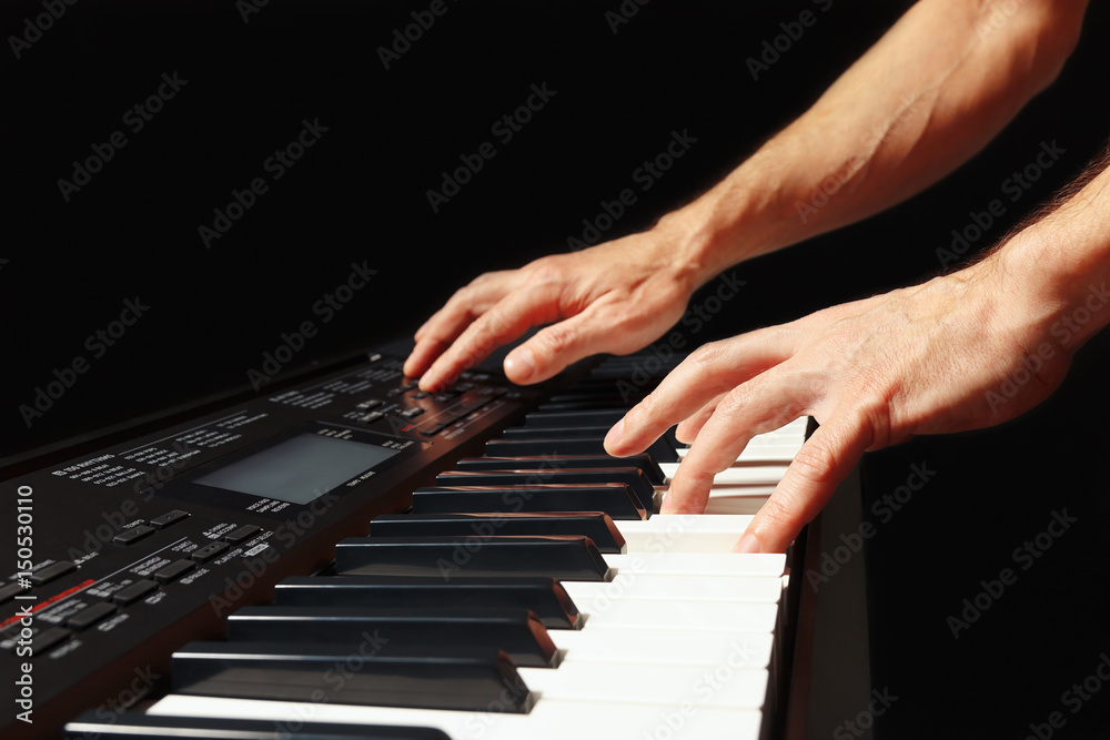 Hands of musician playing the digital piano on a black background