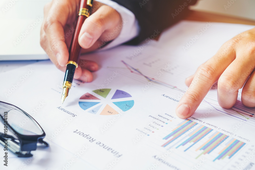 business man holding pen pointing on summary report chart business man holding pen pointing on summary report chart