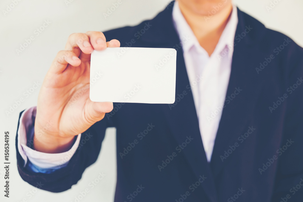Business Man holding white business card on concrete wall background Business Man holding white business card on concrete wall background