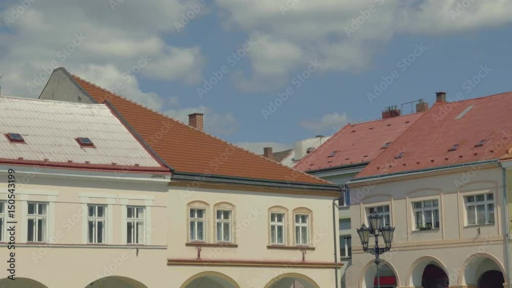 Sunny medieval Renaissance square. View from arcade to row of houses with colorful old facades and blue sky. Age-old gas lamp. Static day shot, color corrected footage. Sunny medieval Renaissance square. View from arcade to row of houses with colorful old facades and blue sky. Age-old gas lamp. Static day shot, color corrected footage.