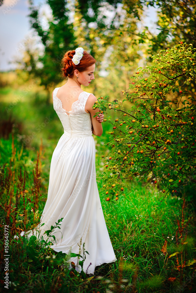 Young beautiful blonde woman in blooming garden. Bride.