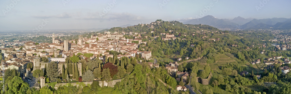 Drone aerial view of Bergamo - Old city (upper town), Italy. Landscape on the city center, the old fortress and its historical buildings during a wonderful blu day