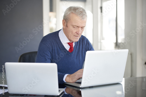 Financial analyzing. Shot of senior financial professional businessman sitting at desk and working on laptops.