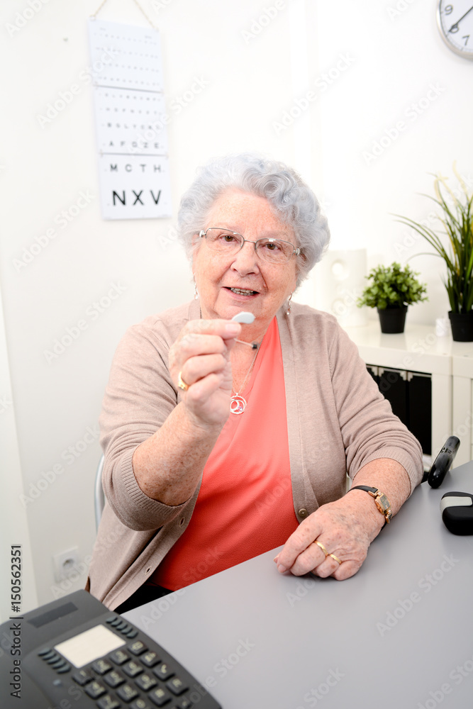 Senior woman in doctor's office showing hearing aid equipment