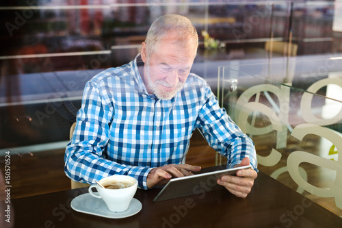Senior businessman working on tablet in cafe