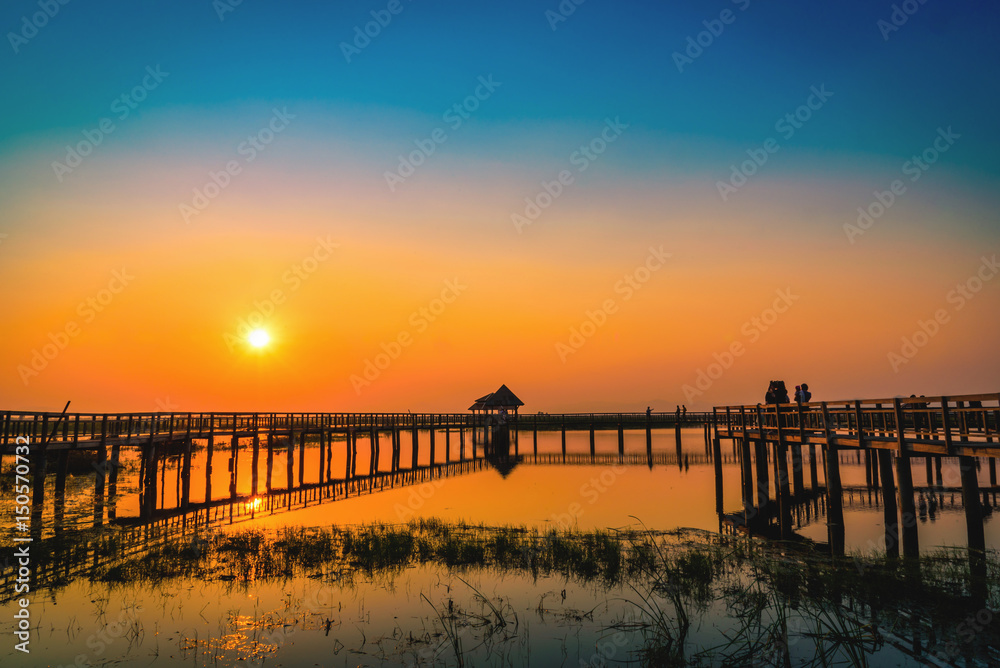 Silhouette old wooden bridge and pavilion in lake at sunset. Vintage tone