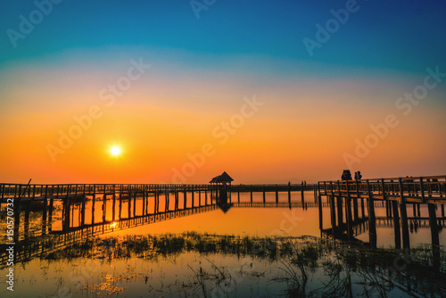 Silhouette old wooden bridge and pavilion in lake at sunset. Vintage tone